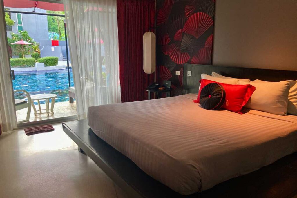 Red Ginger Chic Resort bed with black and red pillows and pool access balcony